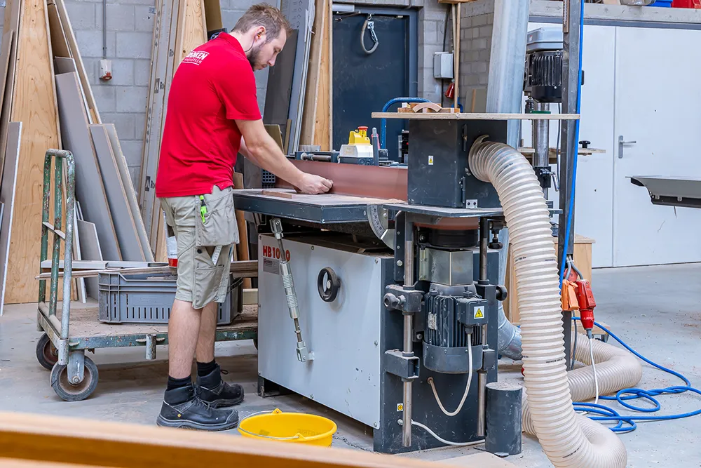 Timmerman aan de schaafmachine in de werkplaats